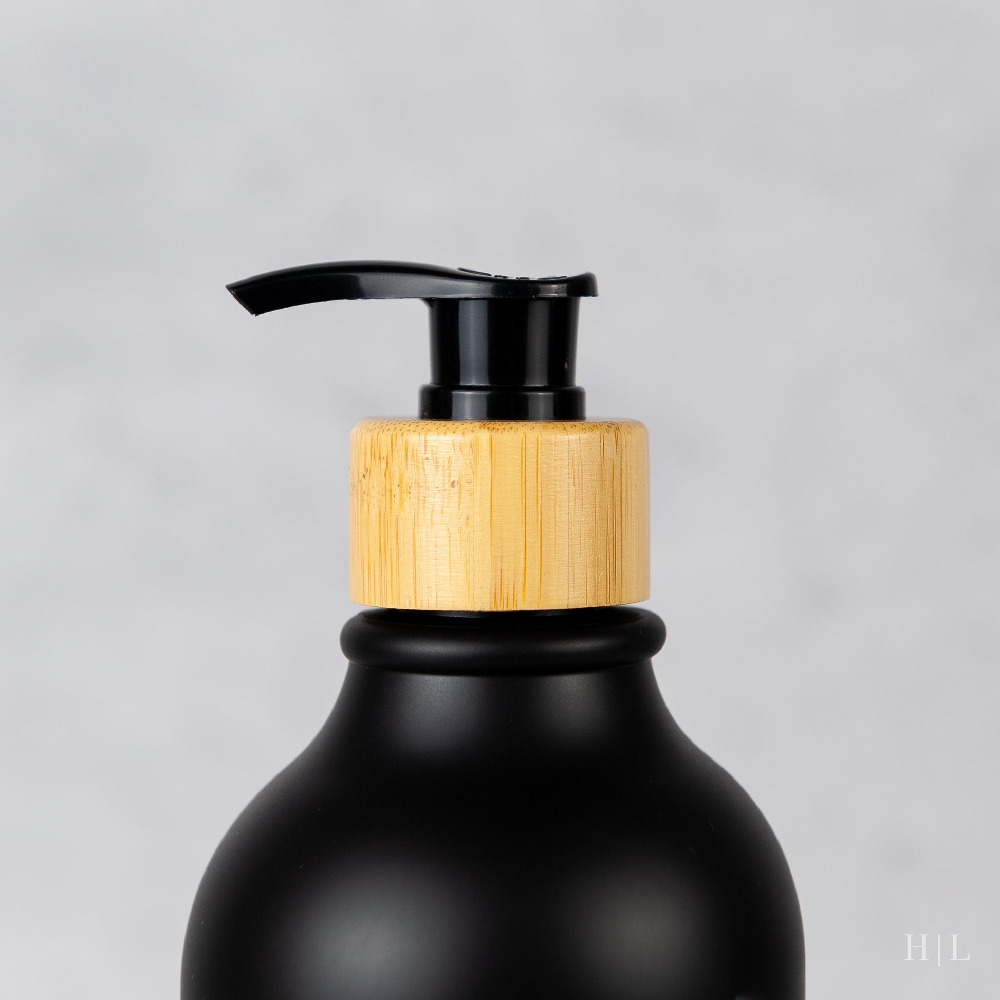 a black bottle with a wooden lid and a black pump